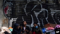 ARCHIVO - Migrantes venezolanos esperan ayuda frente a la Comisión Mexicana de Ayuda a Refugiados en la Ciudad de México, en octubre de 2019.