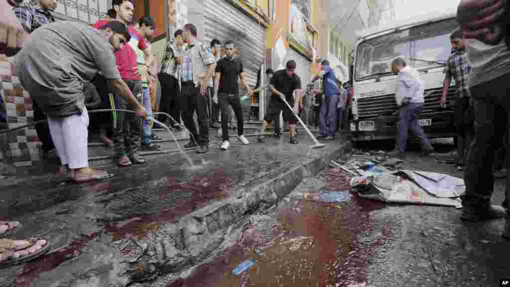 Palestinians wash blood from a sidewalk where seven Palestinians where killed in an Israeli air strike in Gaza City, July 12, 2014.