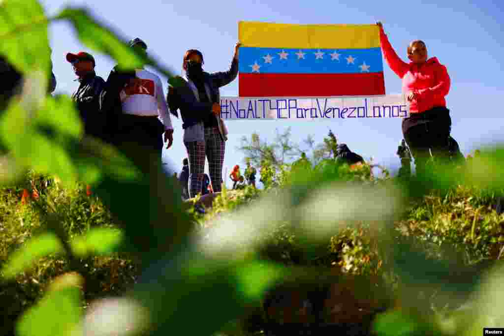 Migrantes venezolanos, algunos expulsados de EEUU a México bajo el Título 42 y otros que aún no han cruzado tras las nuevas políticas migratorias, muestran un cartel que dice "No al Título 42 para venezolanos", a orillas del Río Bravo, en Ciudad Juárez, México, el 26 de octubre de 2022. REUTERS/José Luis González 