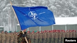 Un soldado alemán enarbola la bandera de la OTAN durante una visita de la entonces ministra de Defensa Ursula von der Leyen a la base de Rukia, Lituania, en 2019. [Foto de archivo]