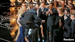 Director and producer Steve McQueen jumps after accepting the Oscar for best picture for his work in "12 Years a Slave" at the 86th Academy Awards in Hollywood, CA, March 2, 2014.