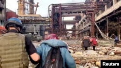 Arhiva - Pripadnik jedinice Azov pomaže ženi tokom evakutacije civila pod vođstvom Ujedinjenih nacija, iz železare Azovstal, nakon gotovo dvomesečne opsade koju su sprovodile ruske snage, tokom njihove invazije na Ukrajinu, u Marijupolju, Ukrajina, 1. maja 2022.