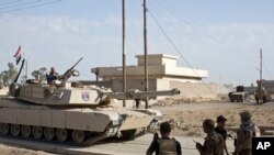Les soldats des forces spéciales irakiennes communiquent par radio alors qu’un char avance dans une ruelle de Bazwaya, à environ 8 kilomètres du centre de Mossoul, Irak, 31 octobre 2016.
