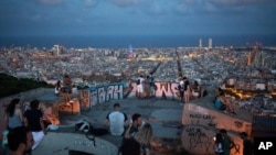 Orang-orang berkumpul di luar menyaksikan pemandangan senja di Barcelona, Spanyol, 25 Juli 2020. (Foto: AP)