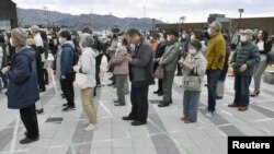 People wearing protective face masks, following an outbreak of the coronavirus disease (COVID-19), form a line while keeping distance from others as they try to watch the Olympic flame during the Tokyo 2020 Olympics Flame of Recovery tour in Ofunato…