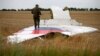 Separatis pro-Rusia bersenjata berdiri di bagian reruntuhan pesawat Malaysia Airlines Boeing 777 setelah jatuh di dekat pemukiman Grabovo di wilayah Donetsk, 17 Juli 2014. (Foto: Reuters)