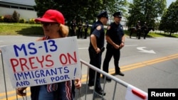 Un partidaria del presidente de EE. UU., Donald Trump, sostiene una pancarta contra la MS-13 antes de un foro sobre la organización de pandillas Mara Salvatrucha (MS-13) en el Centro de Seguridad Nacional de Morrelly en Bethpage, Mayo 2018.