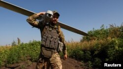 Український військовослужбовець несе розвідувальний дрон на стартову позицію поблизу лінії фронту в Донецькій області. Липень 2023 року. Фото: Reuters/Sofiia Gatilova