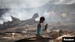  A boy searches for useful items among the ashes of burnt down dwellings after a fire destroyed shelters at a camp for internally displaced Rohingya Muslims in Myanmar's western Rakhine State near Sittwe, May 3, 2016.