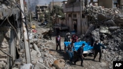 Warga setempat membawa jenazah beberapa korban yang tewas akibat serangan udara antara pasukan Irak dan ISIS di Mosul, Irak, 24 Maret 2017. (AP Photo/Felipe Dana, File)