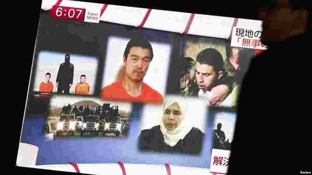 A man walks past a TV screen broadcasting a news program about IS hostages Jordanian pilot Muath al-Kasaesbeh (top R) and Japanese journalist Kenji Goto (top C), along a street in Tokyo, Jan. 29, 2015.