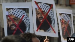 FILE - Indian activists carry placards of the leader of the Pakistan-based Jaish-e-Mohammad group, Masood Azhar, during a protest denouncing an attack on the Indian air force base in Pathankot, in Mumbai, India, Jan. 4, 2016.