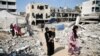 ARCHIVO - Una mujer palestina lleva a un niño mientras caminan entre los escombros de las casas destruidas en ataques anteriores durante la ofensiva militar israelí, en Khan Younis, en el sur de la Franja de Gaza, el 6 de noviembre de 2024