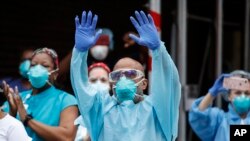 Trabajadores médicos animan y reconocen a los peatones y a los bomberos del FDNY que se reunieron para aplaudirlos a las 7 pm en las afueras del Brooklyn Hospital Center, el 14 de abril de 2020, en Nueva York.