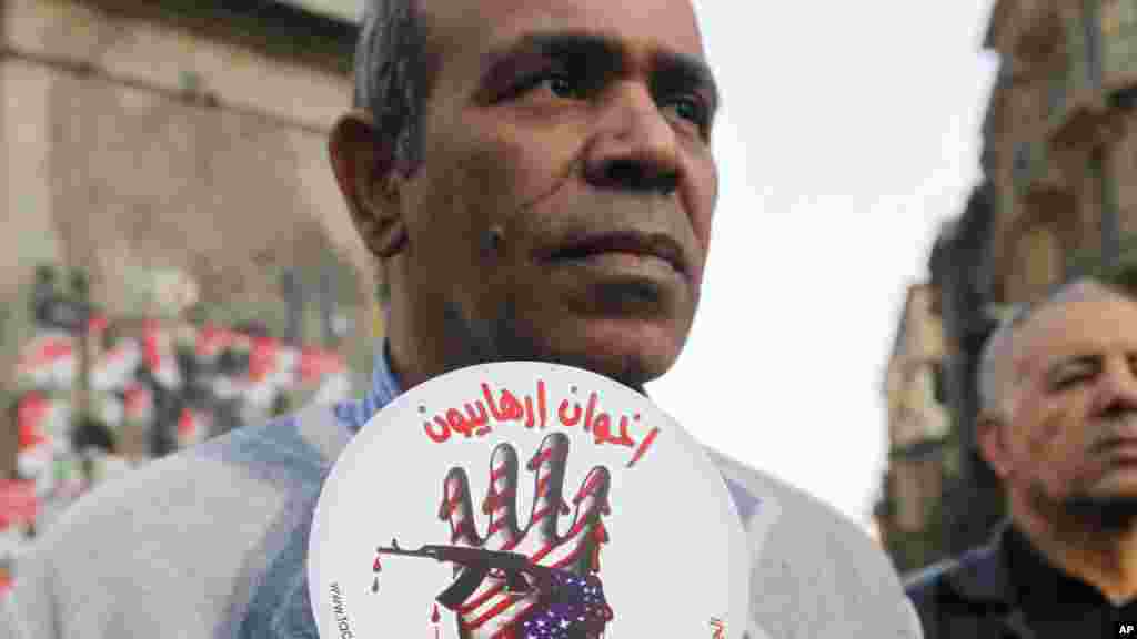 An activist holds a sign with an anti-terrorism picture and Arabic that reads "terrorists brotherhood" during an anti-terrorism demonstration in Cairo, Dec. 26, 2013.