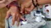 Seorang petugas pemilu membantu seorang perempuan lanjut usia untuk menandai jarinya dengan tinta setelah memberikan suaranya pada Pilkada di Tangerang, Banten, 27 Juni 2018. (Foto: REUTERS/Willy Kurniawan)