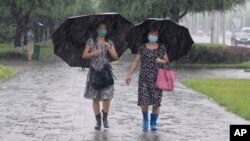 ARHIVA - Žene sa kišobranima šetaju po kiši u Pjongjangu, 5. avgusta 2020. (Foto: AP)