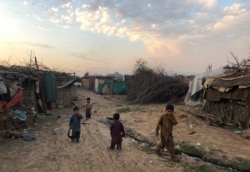 FILE - Children play outside their families' shelters at Afghan refugee camp in Islamabad, Pakistan, Feb. 13, 2020.