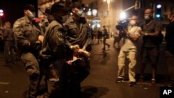 Police carry a protester away as they clear the square outside of Prime Minister Benjamin Netanyahu's residence in Jerusalem, Aug. 22, 2020.