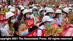 2021年2月21日在曼德勒举行的反政变游行中，医学院学生戴着口罩，举着标语牌聚集在一起。
