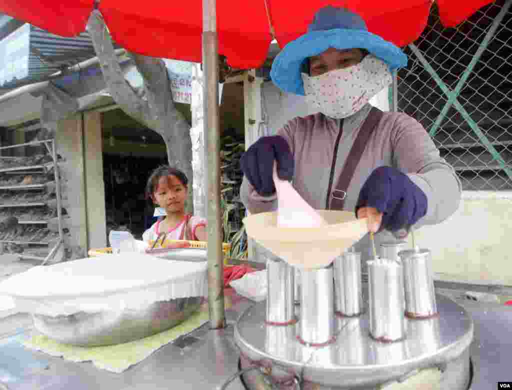 ស្រ្តីជនជាតិវៀតណាមម្នាក់ (មិនមែនមានន័យថាខុសច្បាប់ទេ) ប្រកបរបររកស៊ីលក់បង្អែមនៅសង្កាត់ព្រែកប្រា ខណ្ឌច្បារអំពៅ រាជធានីភ្នំពេញ នៅថ្ងៃសុក្រ ទី១៩ ខែសីហា ឆ្នាំ២០១៦។(ឡេង ឡែន/VOA)