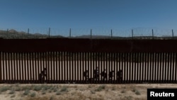 Una vista de un dron muestra a migrantes solicitantes de asilo mientras caminan a lo largo del muro fronterizo tras cruzar la frontera hacia los EEUU, en Jacumba Hot Springs, California, visto desde México, el 16 de mayo de 2024.