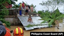 Warga berada di atas atap untuk menghindari banjir, sambil menunggu evakuasi dari tim penyelamat di Libon, provinsi Albay, Filipina, 23 Oktober 2024 (foto: dok). Filipina di urutan teratas negara yang paling berisiko terhadap krisis iklim. 