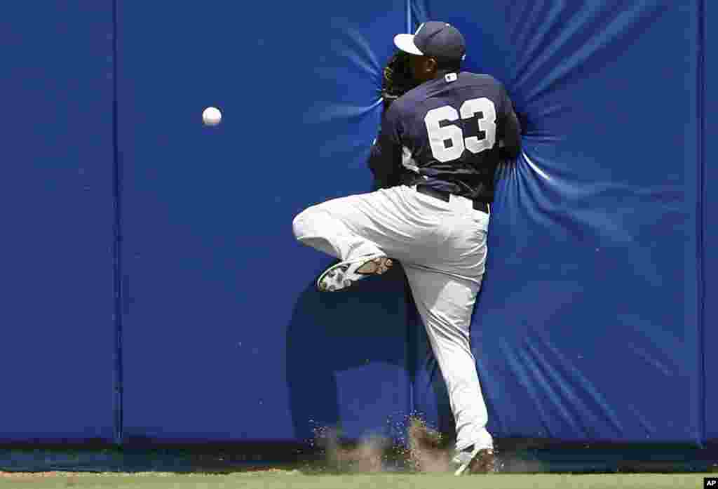 Pemain tengah New York Yankees Jose Pirela menabrak pembatas di pinggir lapangan saat mengejar bola yang dipukul oleh Juan Lagares dari New York Mets pada inning pertama pertandingan eksibisi pelatihan musim semi di Port St. Lucie, Florida. 
