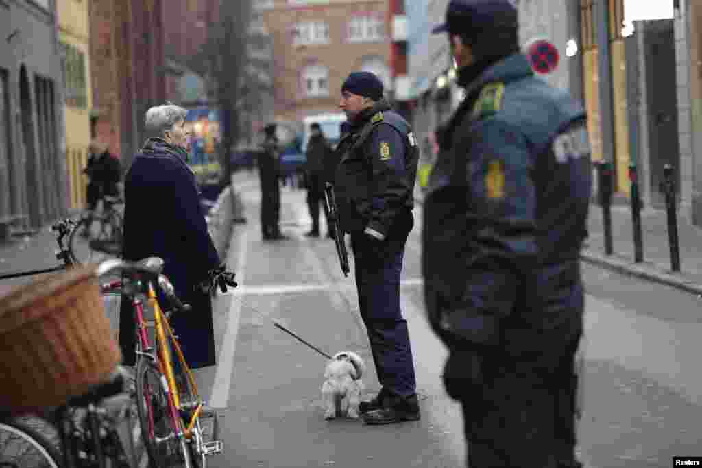 A woman talks to police officers in front of the synagogue in Krystalgade in Copenhagen, Feb. 15, 2015.
