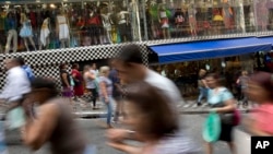 FILE - A photo taken with a slow shutter speed shows people walk through a shopping district in Sao Paulo, Brazil, Dec. 1, 2015.
