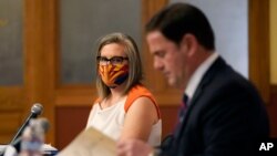 La secretaria de estado de Arizona, Katie Hobbs, observa al gobernador Doug Ducey firmar los documentos electorales que certifican los resultados del voto de noviembre. Lunes 30 de noviembre de 2020.