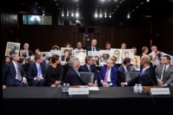 John Hamilton, Wakil Presiden Boeing Commercial Airplanes, dan CEO Boeing Dennis Muilenburg melihat ke arah anggota keluarga korban kecelakaan Boeing 737 MAX yang memegang foto anggota keluarga, di Senat AS, 30 Oktober 2019.