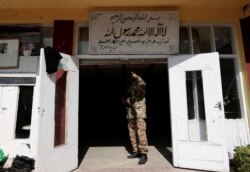 Seorang pejuang Taliban memberi isyarat kepada seorang rekannya saat ia berdiri di dekat pintu masuk sebuah sekolah, di Kabul, Afghanistan, 25 Oktober 2021. (REUTERS)