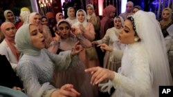 Une mariée égyptienne danse avec ses invitées lors d'une cérémonie de mariage tenue à l'extérieure du Grand Palace dans la province de Menoufia, en Égypte, le 4 novembre 2020.