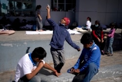 A migrant boy, center, launches a paper airplane while playing with other migrant kids at a plaza near the McAllen-Hidalgo International Bridge point of entry into the U.S., after being caught trying to sneak into the U.S. and deported, Thursday, March 18