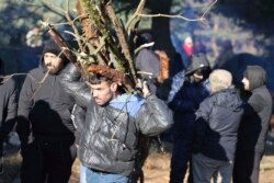 A migrant carries firewood as other migrants from the Middle East and elsewhere gather at the Belarus-Poland border near Grodno, Belarus, Nov. 9, 2021.