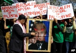 A Muslim protester plays with a portrait of U.S. President Donald Trump with horns and fangs as they try to march toward the Israel Embassy to protest against Trump's decision to recognize Jerusalem as the capital of Israel in metropolitan Manila, Dec. 21, 2017.