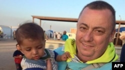 A handout image received from Britain's Foreign and Commonwealth Office on Sept.15, 2014 shows British aid worker Alan Henning holding a child in a refugee camp on the Turkish-Syrian border.