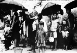 1962年5月拍攝的照片顯示，逃離中國大饑荒的難民在香港排隊領取食物。