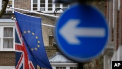 FILE - An EU flag hangs beside the Union flag at Europa House in London, Feb. 17, 2016. EU officials warn that a Brexit would force London to renegotiate free trade deals with EU member states.
