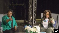 Oprah Winfrey y la candidata a la gobernación de Georgia, Stacey Abrams, saludan a una multitud reunida, en el Teatro Jennie T. Anderson.