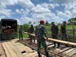 Satgas Pamtas Yonif Mekanis 403/Wirasada Pratista Pos Kotis bersama masyarakat perbatasan memperbaiki jembatan kayu yang rusak di Kampung Woslay, Distrik Senggi, Kabupaten Keerom, Papua, 17 Oktober 2021. (Courtesy: Pendam XVII/Cenderawasih-Papua)