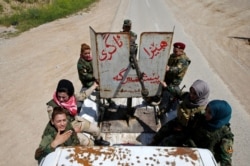 Pejuang perempuan Yazidi Asema Dahir (tengah), 21, berdiri di belakang senjata bersama rekan-rekannya, saat mereka mengendarai truk pickup saat ditempatkan di dekat garis depan perang melawan militan ISIS di Nawaran dekat Mosul, Irak, 20 April 2016. (Foto:REUTERS/Ahmed Jadallah)