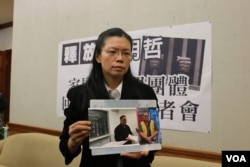 李明哲的妻子李净瑜向媒体展示李明哲以往活动的照片(美国之音杨明拍摄)