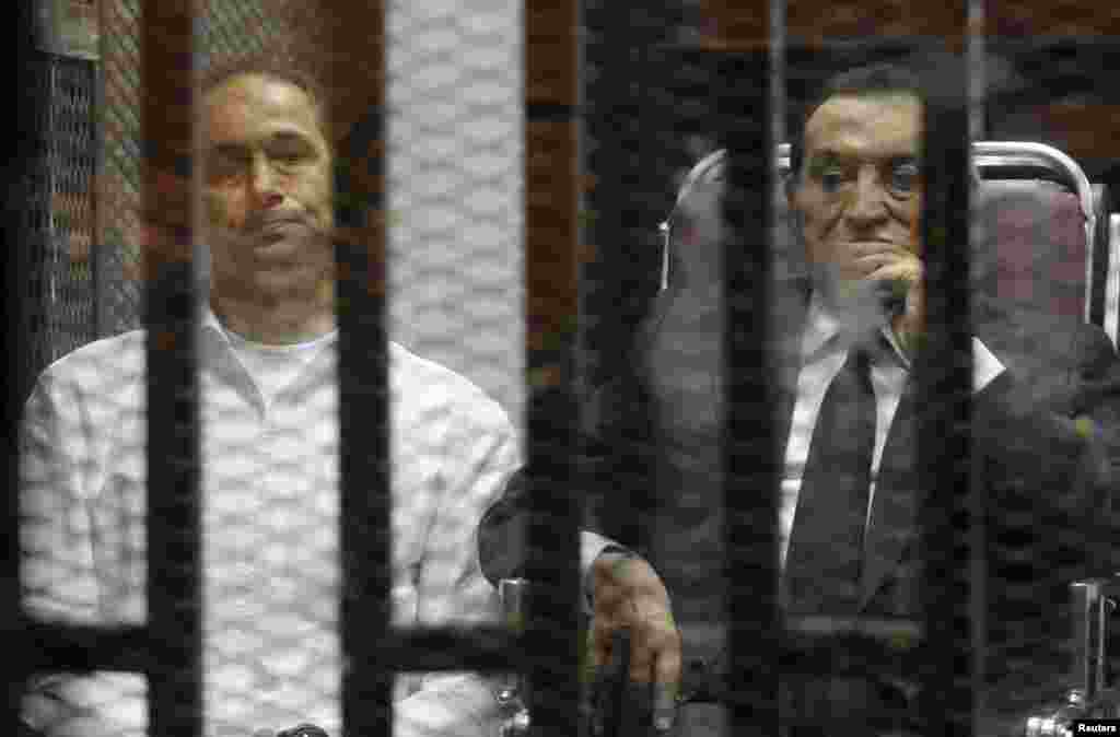 Egypt's ousted president Hosni Mubarak sits next to his son Gamal (left) inside a dock at the police academy on the outskirts of Cairo, May 21, 2014.