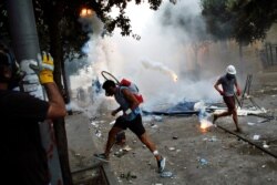Protesters run away from a tear gas canister during clashes with police after this week's deadly explosion at Beirut port which devastated large parts of the capital in Beirut, Lebanon, Aug. 8, 2020.