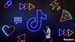 FILE - A man holding a phone walks past a sign of Chinese company ByteDance's app TikTok, in Hangzhou, Zhejiang province, China, Oct. 18, 2019. 