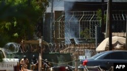 Des agents de sécurité se mettent à l'abri lors d'une prise d'otage, à Ouagadougou, le 2 mars 2018.