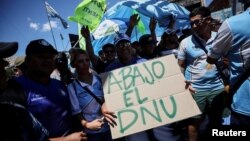 Manifestantes sostienen un cartel con un mensaje contrario al Decreto de Necesidad y Urgencia, con el que el gobierno busca desregular la economía de Argentina, durante un paro nacional, en Buenos Aires, el 24 de enero de 2024.