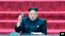 In this Wednesday, April 9, 2014 image made from video, North Korean leader Kim Jong Un holds up parliament membership certificate during the Supreme People's Assembly in Pyongyang, North Korea